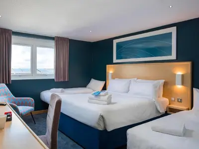 a hotel room with two beds and a desk at Travelodge Harlow in Harlow