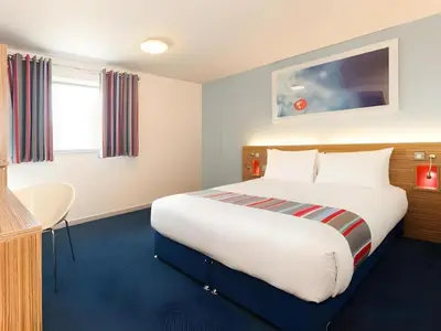 a hotel room with a large bed and a desk at Travelodge Haverhill in Haverhill