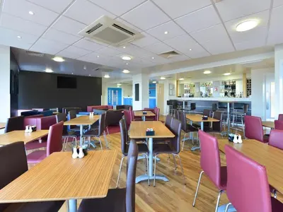 a dining room with wooden tables and purple chairs at Travelodge Haverhill in Haverhill