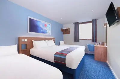 a hotel room with two beds and a tv at Travelodge Haverhill in Haverhill