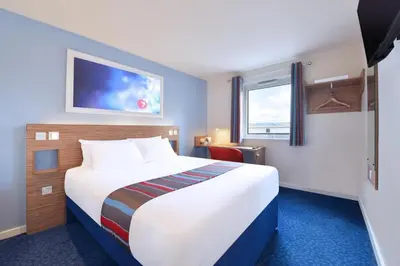 a hotel room with a large bed and a window at Travelodge Haverhill in Haverhill