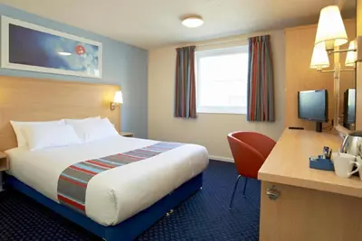 a hotel room with a bed and a desk at Travelodge Ipswich Beacon Hill in Needham Market
