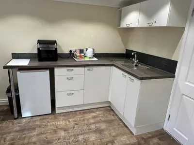 a small kitchen with white cabinets and a sink at The old greengrocers Battlesbridge in Rawreth