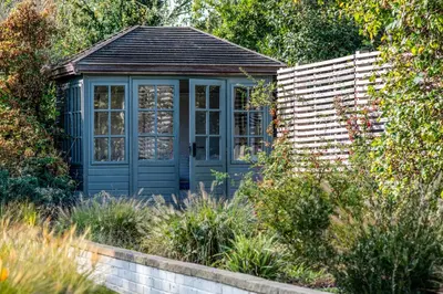 a blue greenhouse in the middle of a garden at Blackshore House in Wenhaston