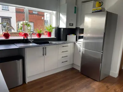 a kitchen with white cabinets and a stainless steel refrigerator at Cozy Organic Tea House in Central Ipswich near Waterfront, University and Hospital in Ipswich