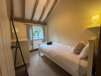 a small bedroom with a bed and a window at Stunning converted barn - Brand sleeps 8 in Sutton