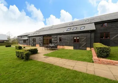 a large house with a patio and a yard at Stunning converted barn - Brand sleeps 8 in Sutton