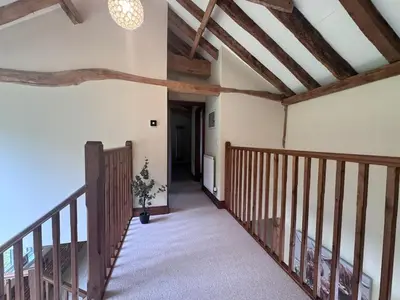 a staircase in a house with wooden beams at Stunning converted barn - Brand sleeps 8 in Sutton