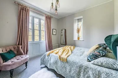 a bedroom with a bed and a chair at Bressingham Lodge by Leap Escapes in Diss