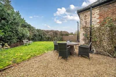 a patio with a table and chairs in a yard at Old Rectory Cottage, Tostock in Tostock