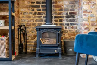 a stove in front of a brick wall at Old Rectory Cottage, Tostock in Tostock