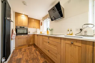a kitchen with wooden cabinets and a microwave at Old Rectory Cottage, Tostock in Tostock