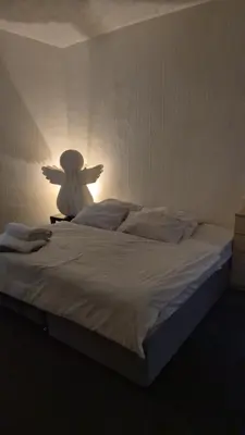 a bedroom with a large white bed with a light on it at Happy house in Southend-on-Sea