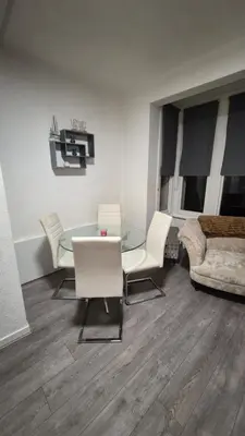 a living room with a glass table and white chairs at Happy house in Southend-on-Sea
