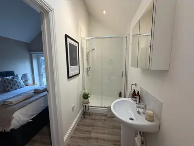 a bathroom with a sink and a shower and a bed at Well-Connected One Bedroom Self-Contained Rural Retreat in Chelmsford