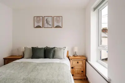 a white bedroom with a bed and a window at La Casa Bianca in Bury Saint Edmunds