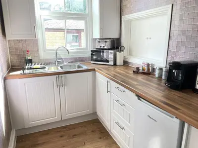 a kitchen with white cabinets and a wooden counter top at Queens - Cosy Central Apartment - JTAP Properties in Cambridge