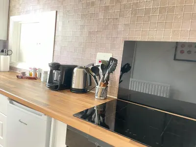 a kitchen counter with a black counter top with utensils at Queens - Cosy Central Apartment - JTAP Properties in Cambridge