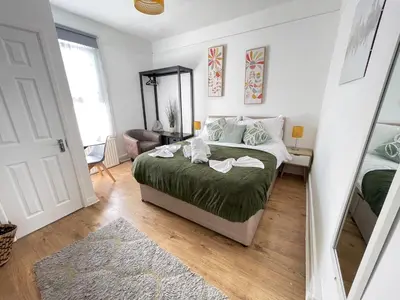 a bedroom with a bed with green sheets and a mirror at Queens - Cosy Central Apartment - JTAP Properties in Cambridge