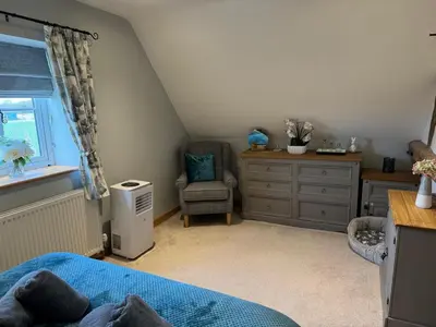 a bedroom with a bed and a chair and a dresser at Cosy Flint Cottage in Thurston