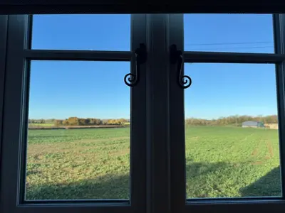 a window with a view of a field of grass at Cosy Flint Cottage in Thurston