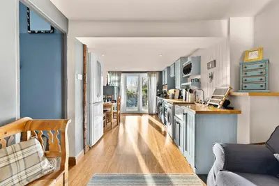 a kitchen and living room with blue cabinets at Abbey House- Character filled 1 bed- sleeps 4 in Bury Saint Edmunds