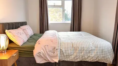 a bed in a room with a window and a bedspread at Cozy Guest Room in Basildon with Shared Facilities in Basildon