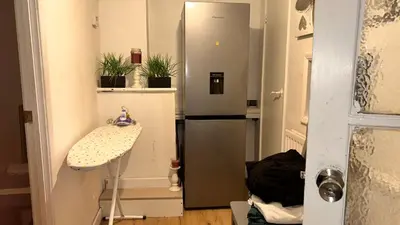 a small kitchen with a refrigerator and a table at Cozy Guest Room in Basildon with Shared Facilities in Basildon