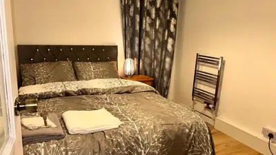 a bedroom with a bed with a silver comforter at Charming Essex Guest Room Comfort, Convenience, and Countryside Charm in Basildon