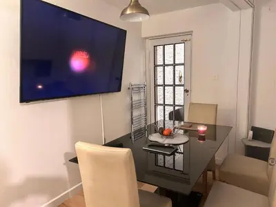 a living room with a table and a television on a wall at Charming Essex Guest Room Comfort, Convenience, and Countryside Charm in Basildon