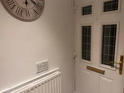 a clock hanging on a wall next to a door at Charming 4-Bedroom House Rental in Basildon, UK in Basildon