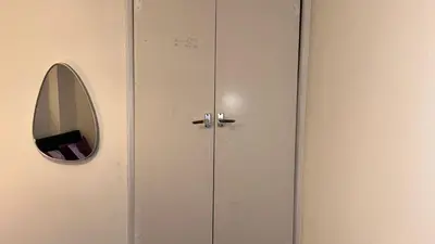 a white locker with a mirror and a door at Charming 4-Bedroom House Rental in Basildon, UK in Basildon
