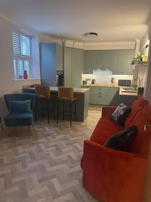 a living room with a red couch and a kitchen at Half Moon Nest - Refurbished throughout for 2026 in Diss
