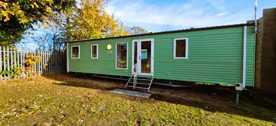 a green train car parked next to a fence at Caravan in Clacton-on-Sea in Little Clacton