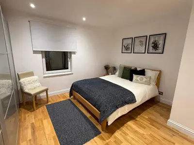 a bedroom with a bed and a chair and a window at Spacious 5 Bed House - Free Parking & WiFi in Basildon