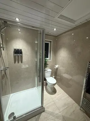 a bathroom with a shower and a toilet and a glass shower stall at Spacious 5 Bed House - Free Parking & WiFi in Basildon