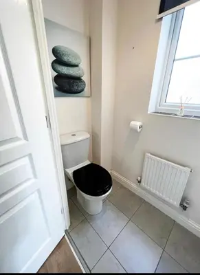 a bathroom with a toilet with a black seat at 4 Bedroom house, Parking, Wi-Fi, Near Town Centre in Ipswich