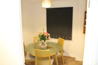 a dining room table with chairs and a vase of flowers at 4 Bedroom house, Parking, Wi-Fi, Near Town Centre in Ipswich