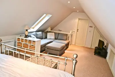 a attic bedroom with a bed and a living room at Idyllic rural retreat, easy access to Cambridge