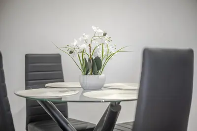 a table with plates and a vase of flowers on it at Chic & Cosy 2 Bed Maisonette with Freeparking near Chelmsford City Centre in Chelmsford