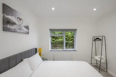 a white bedroom with a bed and a window at Chic & Cosy 2 Bed Maisonette with Freeparking near Chelmsford City Centre in Chelmsford