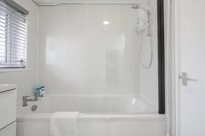 a white bathroom with a tub and a shower at Chic & Cosy 2 Bed Maisonette with Freeparking near Chelmsford City Centre in Chelmsford
