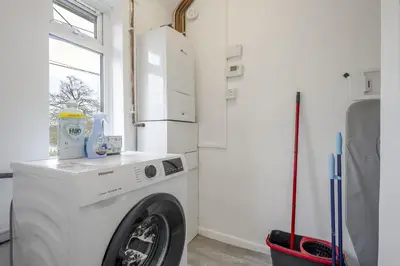 a washing machine in a kitchen with a refrigerator at Chic & Cosy 2 Bed Maisonette with Freeparking near Chelmsford City Centre in Chelmsford