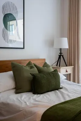 a bed with green pillows on top of it at Station View - Modern Flat Near Centre & Station in Cambridge