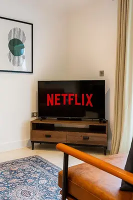 a flat screen tv sitting on top of a wooden entertainment center at Station View - Modern Flat Near Centre & Station in Cambridge