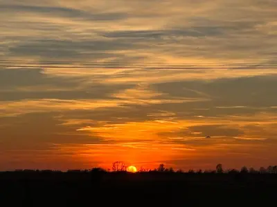 a sunset in a field with the sun in the sky at The Carriage Ely in Coveney