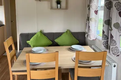 a dining room table with two chairs and a couch at Cabin - Sleeps 6 - Beach 10 minutes drive in Clacton-on-Sea