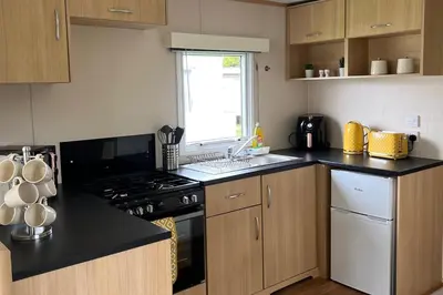 a kitchen with a stove top oven next to a window at Cabin - Sleeps 6 - Beach 10 minutes drive in Clacton-on-Sea