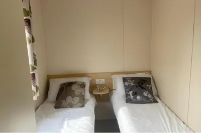 a small room with two beds and a side table at Cabin - Sleeps 6 - Beach 10 minutes drive in Clacton-on-Sea