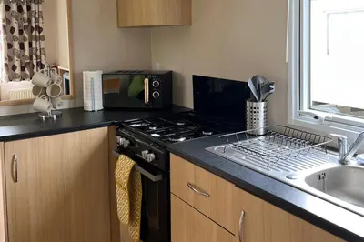 a kitchen with a stove top oven next to a sink at Cabin - Sleeps 6 - Beach 10 minutes drive in Clacton-on-Sea